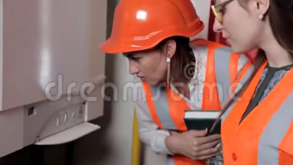 两名女工程师检查锅炉房供暖系统设备的技术数据视频的预览图