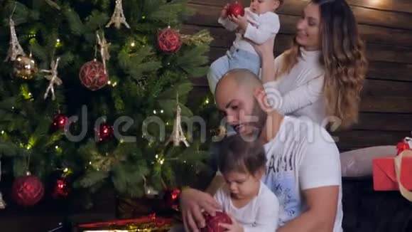 家庭装饰圣诞树两个小女孩在圣诞夜和爸爸妈妈在一起视频的预览图