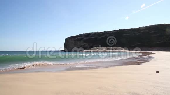 热带海滩上的小波浪在沙滩蓝天和背景下的悬崖上破碎视频的预览图