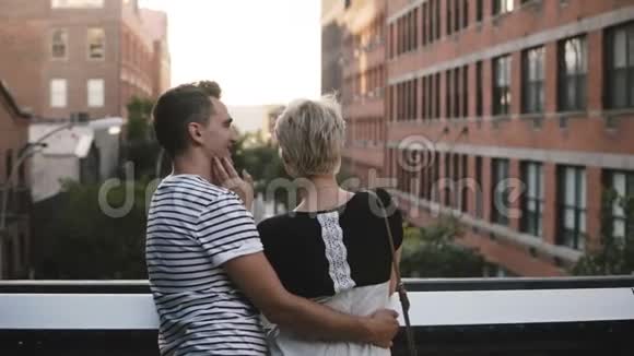 美丽的年轻浪漫夫妇站在桥上拥抱交谈欣赏着令人惊叹的纽约市风景视频的预览图