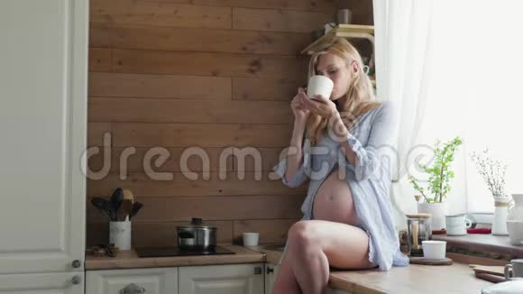 迷人的孕妇在厨房喝茶孕妇坐在桌子上喝茶视频的预览图