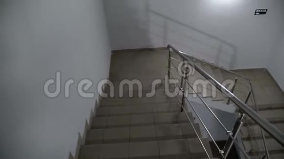 在现代办公大楼里从黑暗的楼梯上走下来的4K镜头视频的预览图
