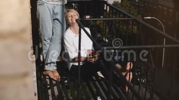 美丽的多民族夫妇享受着咖啡的早晨在纽约阳光明媚的小阳台上互相微笑视频的预览图