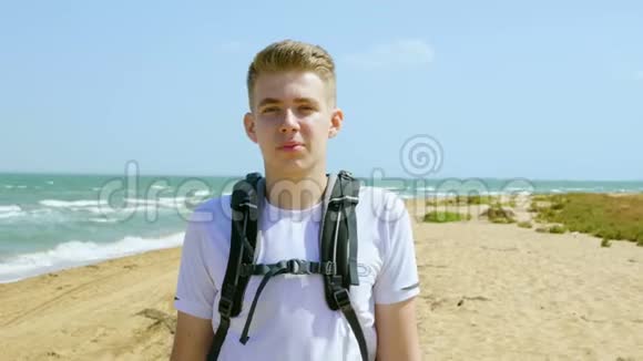 一位年轻游客在海边沙滩上的肖像视频的预览图