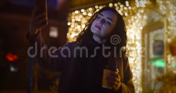 有魅力的女人在夜晚城市的节日灯光的背景下自拍视频的预览图