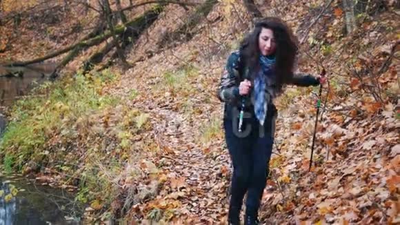 斯堪的纳维亚半岛的一位留着卷发的年轻女子在森林里散步女人绕着小溪走视频的预览图