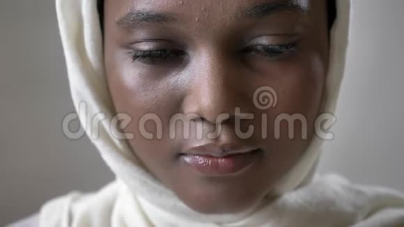 戴头巾的年轻悲伤的非洲穆斯林女孩正在抬头看着镜头宗教概念灰色背景视频的预览图