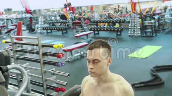 可爱的年轻男性健美运动员与练习机训练肩膀肌肉视频的预览图