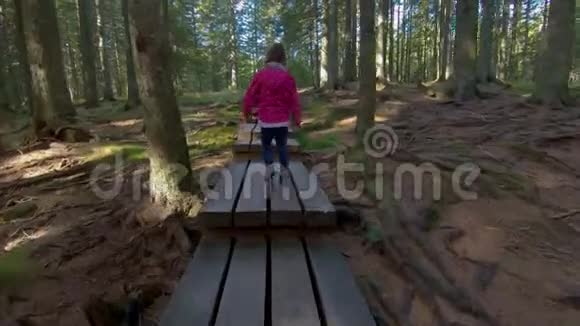 小女孩徒步穿越森林的人行桥视频的预览图