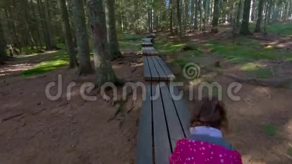 小女孩徒步穿越森林的人行桥视频的预览图