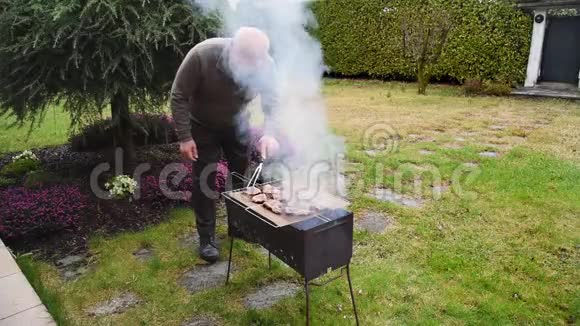 老人把肉烤在炭烤架上视频的预览图