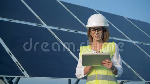 户外太阳能电池旁边站着一位女工程师微笑着视频的预览图