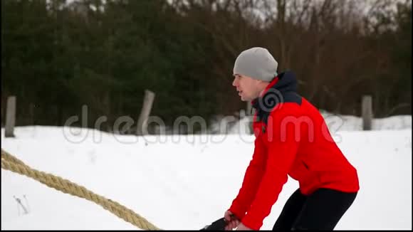 男子用绳子在功能性训练中健身冬季在交叉健身中锻炼慢动作视频的预览图