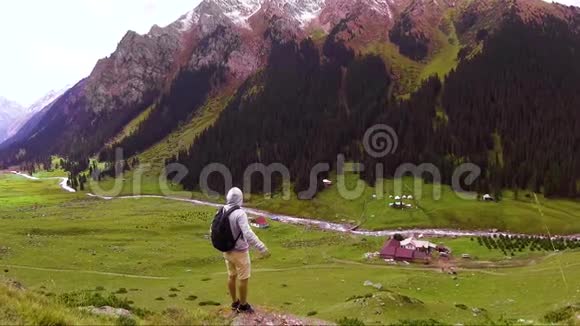 一个背着背包的年轻旅行者站在山峡的边缘环顾四周视频的预览图