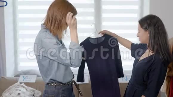 两个漂亮的年轻女人正在从事衣柜的分析女朋友选择服装并挑选图片视频的预览图