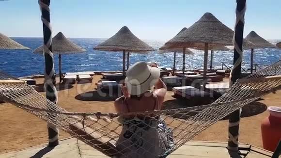 女人在海滩上的吊床上发冷在海上度假在海滩上放松大海和娱乐沙滩和蓝色视频的预览图