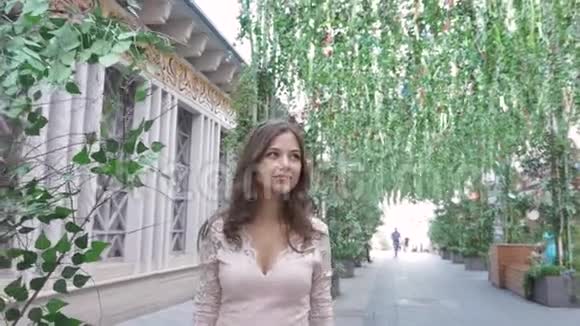 一个年轻的女孩走在城市的街道上漂亮的花饰晴天的夏天视频的预览图