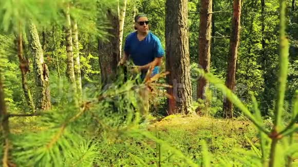 一个在树林里休息的人穿上背包起身离开森林视频的预览图