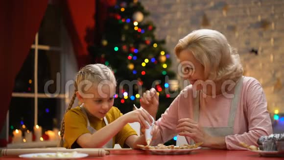 兴奋的女孩用奶奶装饰圣诞饼干家庭节日传统视频的预览图