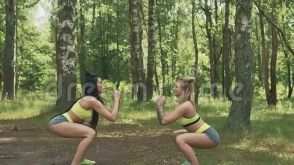 两个年轻的女人蹲在公园里户外运动纹身的健身模特视频的预览图