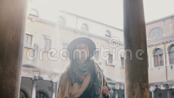 美丽的女性专业摄影师带着相机在威尼斯老城的古建筑柱子上拍照视频的预览图