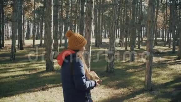 穿着帽子和夹克在森林里的少女松树视频的预览图