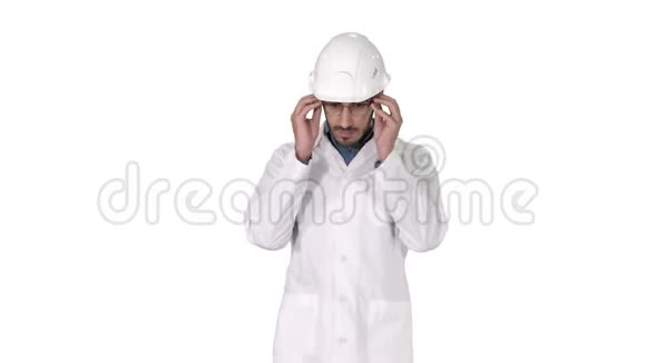 年轻的工程师穿着长袍和头盔戴着眼镜走在白色的背景上视频的预览图
