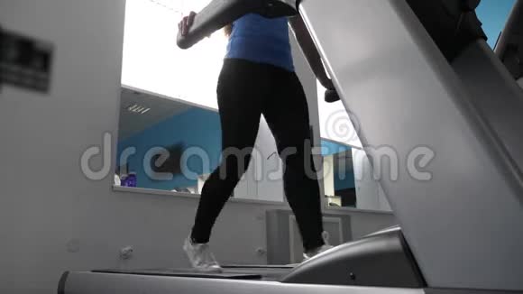 健身俱乐部苗条的女孩从事在跑步机上行走跑步机上的女孩有氧运动负荷加强肌肉力量视频的预览图