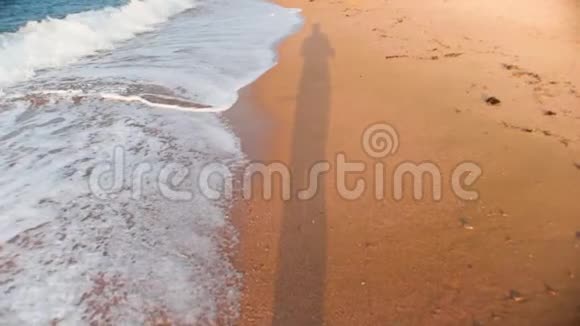 日落时人们在沙滩上散步的慢镜头视频的预览图