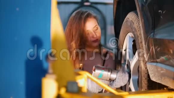 女机械师穿着工作服头发凌乱把汽车车轮弄乱了视频的预览图