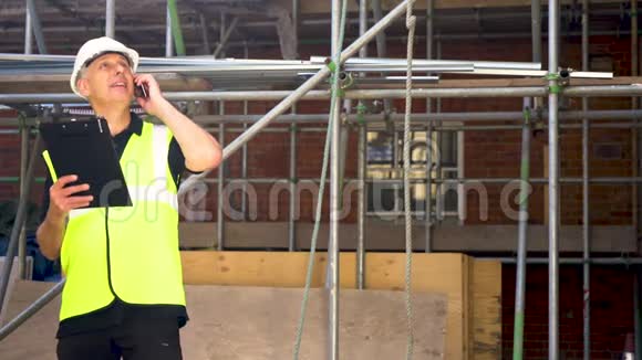 男建筑工领班建筑工人在建筑工地上穿着硬帽子写在剪贴板上视频的预览图