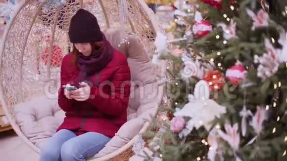 一个年轻漂亮的女人在圣诞商店使用智能手机女人在商店里走来走去挑选圣诞装饰品视频的预览图