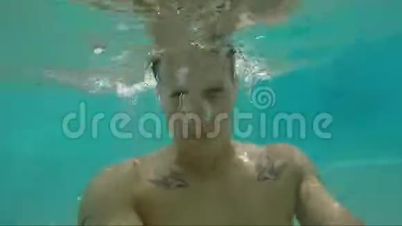 英俊的年轻人在游泳池游泳水下射击视频的预览图