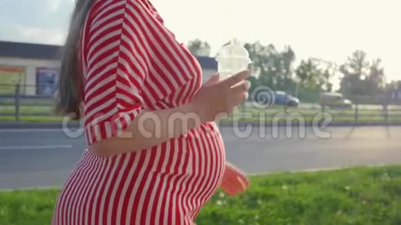等待孩子的孕妇女人从稻草中喝橙汁在城市里散步的概念视频的预览图