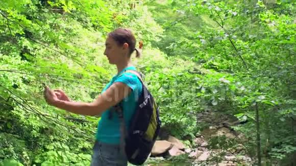 可爱的女性博主用智能手机拍摄带有绿色热带山林背景的自拍照片视频的预览图