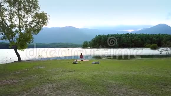 女孩坐在湖畔冥想瑜伽姿势视频的预览图