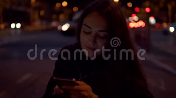 有魅力的女人晚上坐在街上用手机视频的预览图