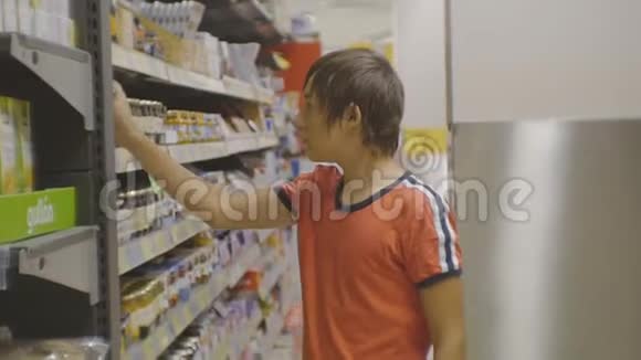 超市里的青少年穿着红色t恤的白人少年选择并把食物篮蜂蜜放进玻璃罐里视频的预览图