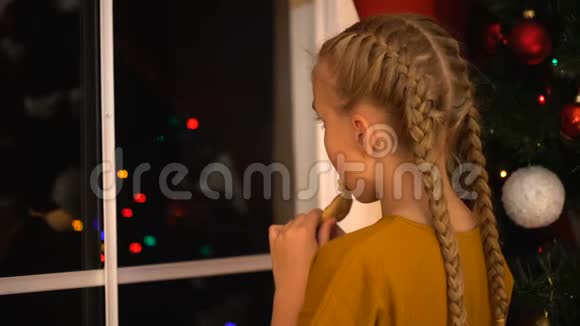 小女孩透过窗户看着吃饼干等待着父母的圣诞前夜视频的预览图