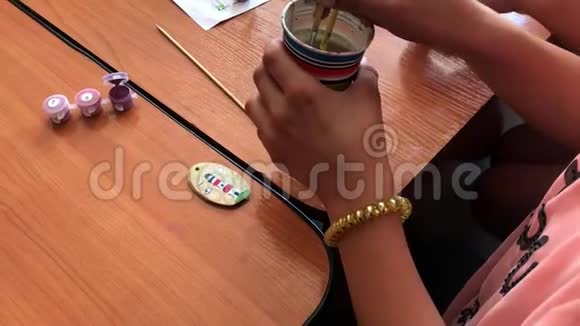 一个孩子画一个绿色的小木刻的特写镜头手工艺活动视频的预览图