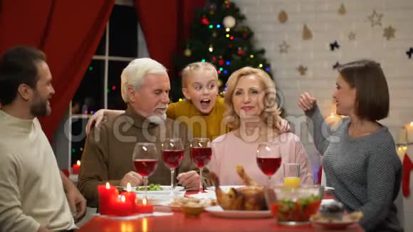 一家人拥抱着微笑着看着圣诞晚餐的镜头画像视频的预览图