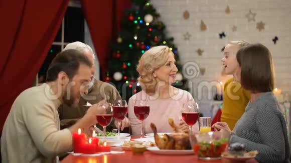 快乐可爱的女孩拥抱祖父母一家人吃传统的圣诞晚餐视频的预览图