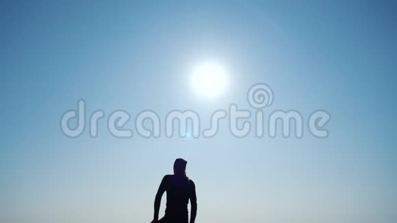 年轻的有灵感的人旅行者站在海面上的山顶上对抗美丽的蓝天剪影视频的预览图
