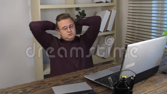疲惫的商人在笔记本电脑附近的办公室椅子上摇摆视频的预览图