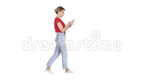 美丽的年轻女子在白色的背景下在手机上行走和阅读短信视频的预览图