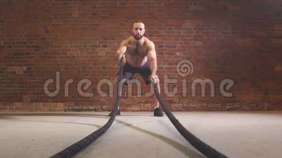 年轻的白种人在健身房用战绳锻炼慢动作视频的预览图