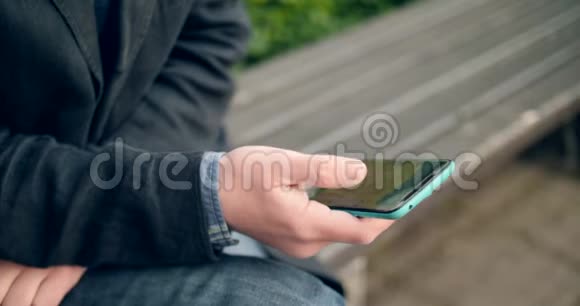 欧洲男人在公园里使用智能手机视频的预览图