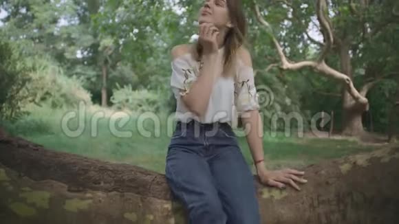 小女孩坐在一棵树的厚枝上视频的预览图