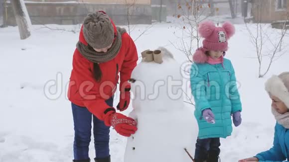 户外冬季家庭游戏妈妈和两个女儿一起塑造了雪人视频的预览图