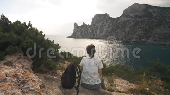 女性旅行者看着大海和山脉视频的预览图